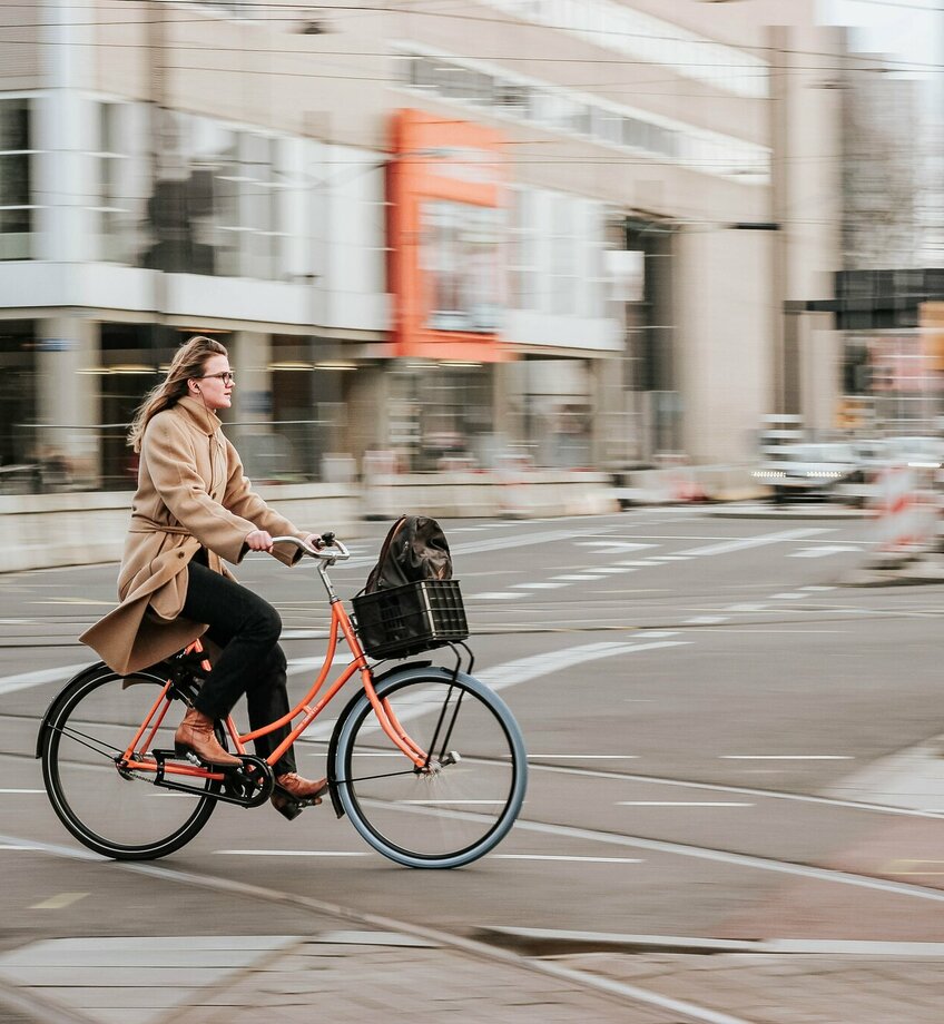 Dame op oranje fiets in stadscenter