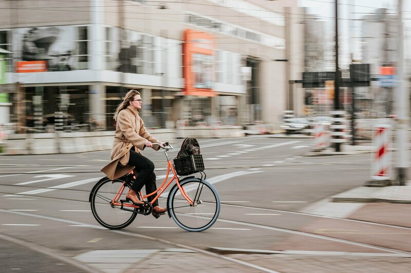 Dame op oranje fiets in stadscenter